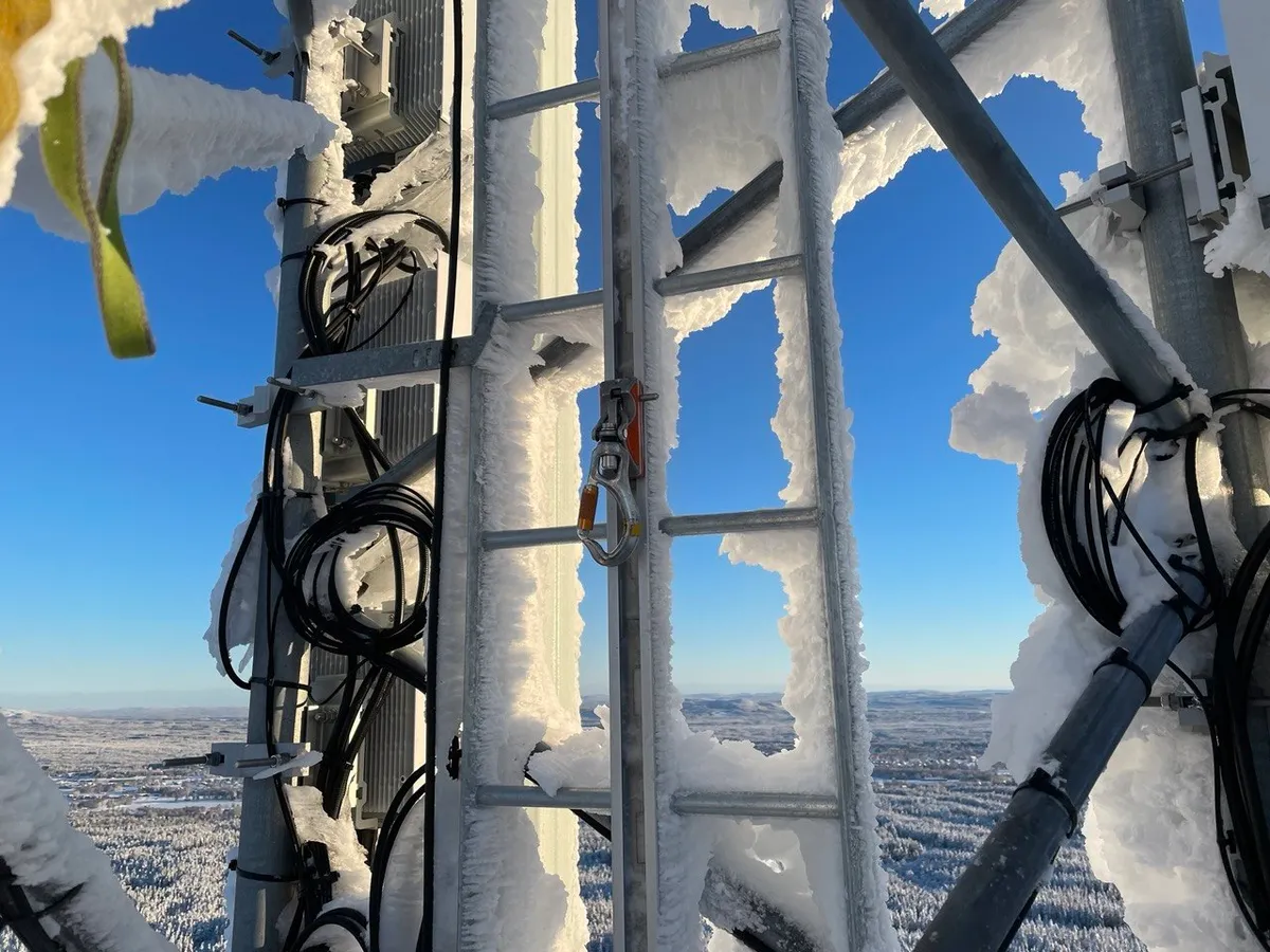 Rime-covered ladder, cables and equipment on a tower in winter, with a fall-arrest device on the ladder